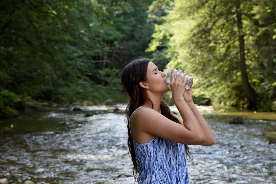 lady drinking water in forest